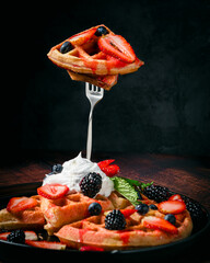 Gofres (waffle, wafol, wafel o wafle) adornados con frutas del bosque, sirope y crema batida