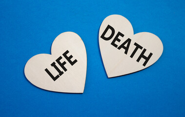 Life or Death symbol. Concept word Life or Death on wooden hearts. Beautiful blue background....