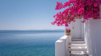 A classic Mediterranean scene: a whitewashed building with a closed white door and staircase. Bright fuchsia bougainvillea cascades down the top of the building, with a calm turquoise sea