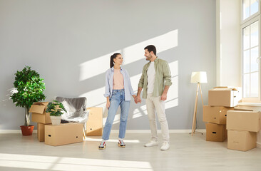 Happy couple, young family celebrate relocation standing in new modern apartment, husband, wife feels happy, start living together, enjoy moving day to new flat, starting cohabitation after marriage