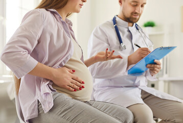 Young pregnant woman having appointment with doctor. Future mother sitting in obgyn office and...