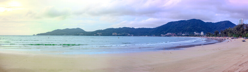 Patong Beach in the beautiful island of Phuket Thailand. Lovely colours of the sky at sunset and the turquoise blue waters of the Andaman sea people parasailing and swimming