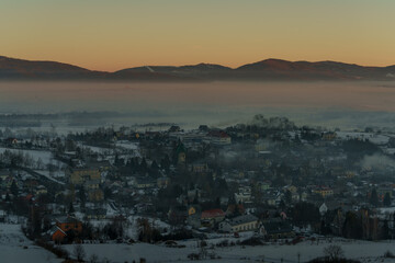 Winter mountain valley with village covered in smog at sunrise