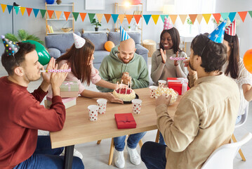 Friends happy birthday candle cake celebration at home, funny friendly group portrait applauding on...