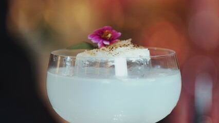 Closeup hand bartender using strainer in vodka coconut smooth fizzy cocktail at luxurious counter...
