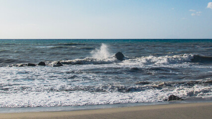 Waves of the Mediterranean Sea crash on a cliff along a Sicilian beach in Italy during a summer afternoon