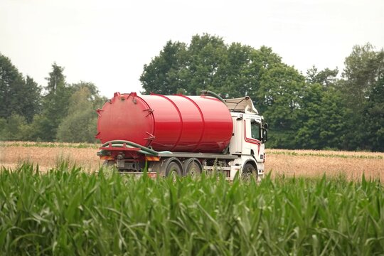 Czerwona cysterna jadąca wiejską drogą