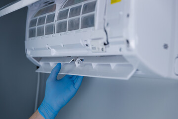 Expert demonstrates the maintenance of an air conditioning unit by removing its filter system...