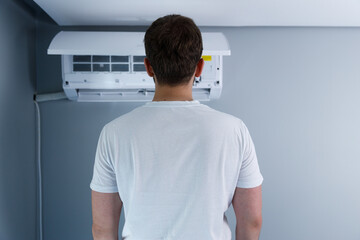 A person standing in front of an air conditioning unit, emphasizing the importance of a comfortable...