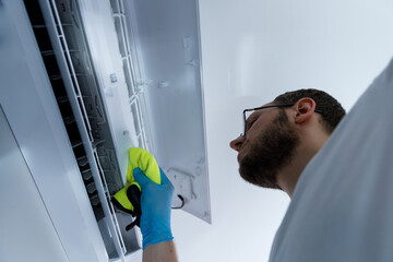 A person thoroughly cleaning an air conditioning unit, ensuring optimal performance and hygiene by...