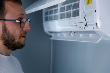 Person Inspecting an Air Conditioner: Maintenance and Repair Insights for Optimal Temperature...