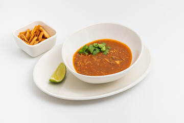 Spicy Mexican chicken soup with noodles, garnished with fresh cilantro and lime wedge