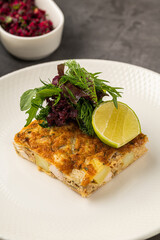 Spanish tortilla with potato and chicken, topped with fresh greens and lime