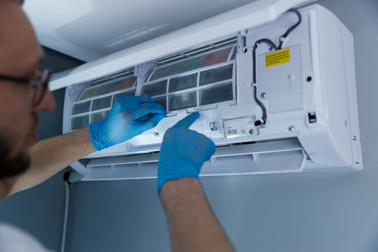 Professional Technician Performing Maintenance on a Split Air Conditioning Unit with Focus on Filter Replacement and Indoor Unit Care in a Residential Setting
