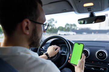 Man in a Car Holding a Smartphone with a Green Screen While Driving Thoughtfully Contemplating...