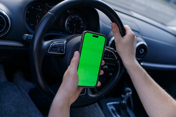 A Driver Holding a Smartphone with a Green Screen While Steering - The Modern Blend of Technology...