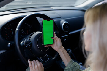 A Close-Up in a Car Interior Featuring a Hand Holding a Smartphone with a Green Screen, Ideal for...