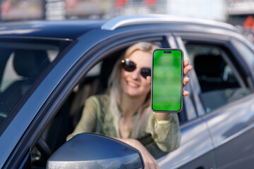 Cheerful Woman Displays Smartphone with Green Screen from Car Window, Showcasing Technology and...