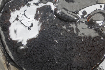 Close-up view of black tar-like substance with unique texture in open container under natural light