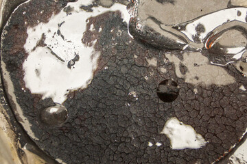 Close-up view of black tar-like substance with unique texture in open container under natural light