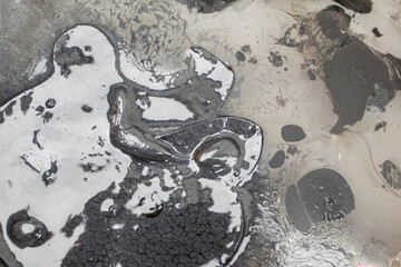 Close-up view of black tar-like substance with unique texture in open container under natural light