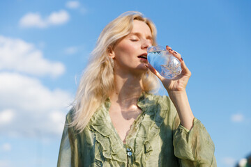 Refreshing Moments: A Woman Enjoys a Cold Drink Under the Clear Blue Sky, Embracing the Beauty of...