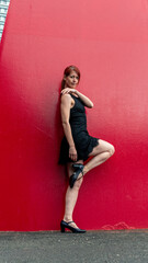Elegant dancer posing against vibrant red wall