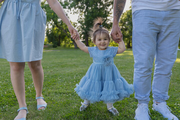 Fototapeta premium First steps. Baby learning to walk, with help of mothers and fathers hands.