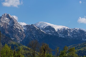 A mountain range with snow-capped peaks is pictured against a clear blue sky in Zakopane - Lesser Poland - Poland
