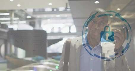 Mid adult man at station gates on smartphone enabling security graphics around phone securing data