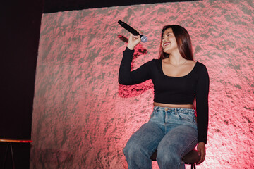 beautiful young Latina woman with a microphone in karaoke or singing