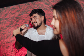 LGBT friends holding a microphone singing in a bar or karaoke