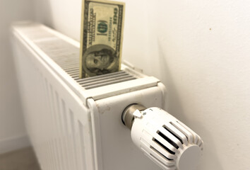A heating radiator battery from which bills stick out. The concept of high heating expenses. Rise...