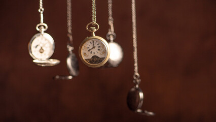 Pocket watch, beautiful and antique pocket watches hanging in front of an abstract background, selective focus.