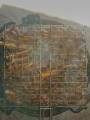 In this overhead view, meat cells sizzle on charcoal, surrounded by wisps of smoke and dripping grease, freshly grilled to perfection for a mouth-watering barbecue.
