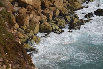 Waves crash against the rocky shoreline of Sagres, Algarve, Portugal. The steep cliffs and rugged coast highlight the region&rsquo;s wild Atlantic beauty.