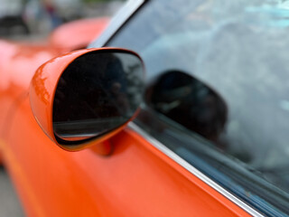 Side mirror on orange classic car closeup