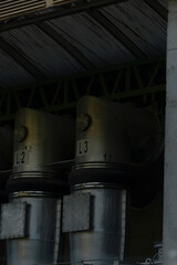 A long row of shiny metal containers is meticulously lined up in a dimly lit, dark room, creating...