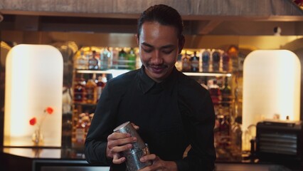 Asian smart bartender shaking mixed cocktail preparing to serve at luxurious counter preparation, making special drink looking at camera fronted view. Special refresh drink nightlife luxury. Vinosity.