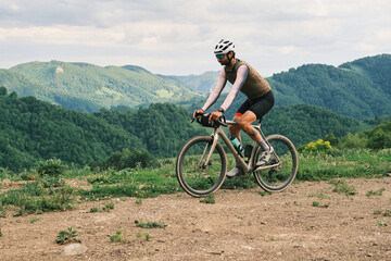 A cyclist enjoys a scenic ride through rolling green hills.  The gravel bike and mountainous...