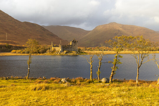 Kilchurn Castle in den schottischen Highlands bei Sonnenuntergang, warme Lichtstimmung &uuml;ber dem See Loch Awe, Enten schwimmen vor der historischen Burgruine in ruhiger Landschaft