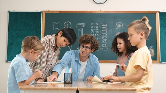 Smart teacher explain idea while diverse children drawing mind map while group of diverse student working together to do class work. Attractive instructor teaching and talking about working. Pedagogy. - Powered by Adobe