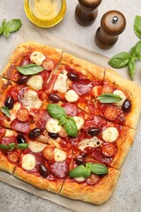 Tasty square homemade pizza and spices on grey background, flat lay