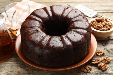 Tasty chocolate bundt cake, walnuts and tea on wooden table, closeup