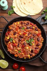 Tasty chili con carne in baking dish and flatbread on wooden table, flat lay