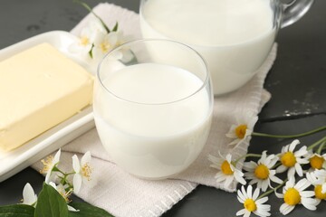 Fresh dairy products and flowers on grey wooden table, closeup
