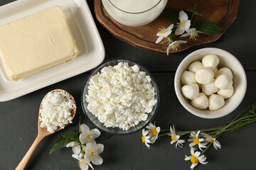 Fresh dairy products and flowers on grey wooden table, flat lay