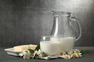 Fresh dairy products and flowers on grey wooden table against textured background