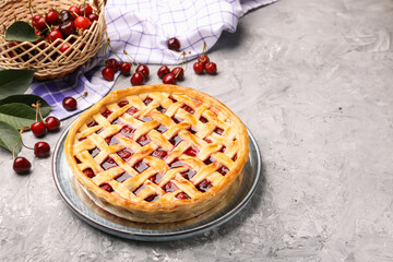 Tasty cherry pie and berries on grey textured table. Space for text