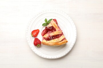 Piece of tasty strawberry pie and berries on white wooden table, top view